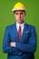 Young businessman with hardhat against green background