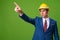 Young businessman with hardhat against green background