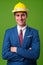 Young businessman with hardhat against green background