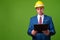 Young businessman with hardhat against green background