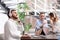 Young businessman with headphones, laptop and his colleagues at table