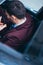 Young businessman looking at his cellphone while comfortably sitting at the front seat in his luxury limo