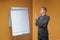 Young businessman points with his finger to a flip chart in the office - with copyspace. Sceptical, critical or