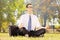 Young businessman seated on a green grass meditating in a park