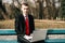 Young businessman sitting with a laptop on a park bench. guy in a suit with a red tie. freelance. remote work concept.