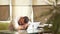 Young businessman sleeping and overworked near laptop at office. He is 20-30 years old in white shirt and black plant