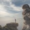 Young businessman standing on edge of rock mountain