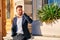 Young businessman standing at the entrance of a building and tal