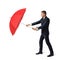 A young businessman stands on white background and hides from harsh environment behind an open red umbrella.