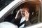 Young businessman suffers terrible headache while siting in his car with open window, safety driving concept