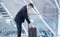 Young businessman in a suit with his rolling luggage in an airport