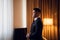 A young businessman in a suit standing in a hotel room, looking