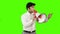 Young businessman talking into a megaphone on green background