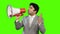 Young businessman talking into a megaphone on green background