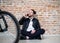 A young businessman with telephone sitting on the floor in office.