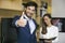 Young businessman with thumb up standing with businesswoman in o