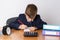 The young businessman is tired of work, draws. On the table is a calculator, next to a mini shopping trolley, a clock and folders