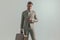 Young businessman unbuttoning suit while holding luggage