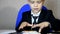 Young businessman using a laptop. Fashion child handsome boy in modern office. sits at a table in an armchair and counts money coi