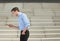 Young businessman walking outdoors and looking at mobile phone