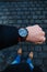 Young businessman wearing watch with coat. Winter in the city. Lifestyle photo. Urban scene in the Prague.