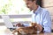 Young businessman is working on a laptop on an open terrace, smiling and stroking a kitten. Freelance concept