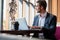 Young businessman working on laptop, sitting in hotel lobby waiting for someone.