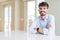 Young businesss man sitting on white table with a happy and cool smile on face