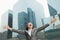 Young businesswoman with arms outstretched and head back among skyscrapers, Beijing