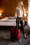 Young businesswoman arrives in a hotel room with red suitcase an