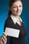 Young businesswoman with blank business or note card on blue background