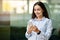 A young businesswoman checks her smartphone with a content smile, wearing a smart watch