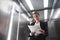 Young businesswoman is concentrated on reading the documentation in the elevator. Female office worker is focused while checking