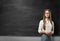 Young businesswoman with glasses standing in front of blank blackboard