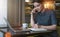 Young businesswoman in gray dress sitting at table in cafe, talking on cell phone while taking notes in notebook.