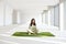 Young businesswoman with laptop while sitting on grass carpet in empty office