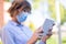 Young businesswoman in mask using tablet in park selective focus