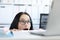 Young businesswoman peering over her desk in office in wide eyed horror or amazement