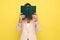 Young businesswoman in pink suit hiding behind book