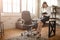 Young businesswoman sit on table and work in room. She hold tablet and smile. Positive and cheerful.