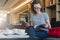 Young businesswoman sits on sofa in hotel lobby, restaurant, cafe, drinks coffee and reads book, magazine, catalog.