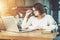 Young businesswoman sitting in cafe at table in front of laptop and looking closely at monitor, holding glasses.