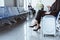 young businesswoman with smartphone and luggage sitting at departure lounge