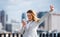 A young businesswoman with smartphone standing on a terrace, expressing excitement.