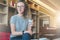 A young businesswoman in stripped t-shirt and glasses sits on sofa in hotel lobby, restaurant, cafe and holds glass of