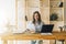 Young businesswoman woman is sitting at kitchen table, reading documents,uses laptop,working, studying.