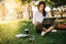 Young businesswoman working on her notebook in park. Freelancer female sitting on grassy lawn using laptop computer with her diary