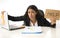 Young busy desperate Latin businesswoman holding help sign sitting at office desk in stress worried