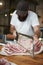 Young butcher sawing meat at a butcher\'s shop, vertical