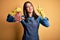 Young butcher woman wearing apron holding raw beef steak over yellow isolated background surprised with an idea or question